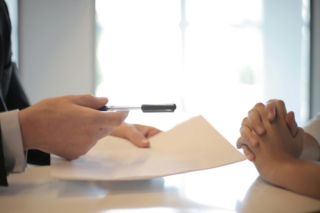 Hands holding a pen over insurance documents in an office, symbolising insurance AI and data-driven decision-making.